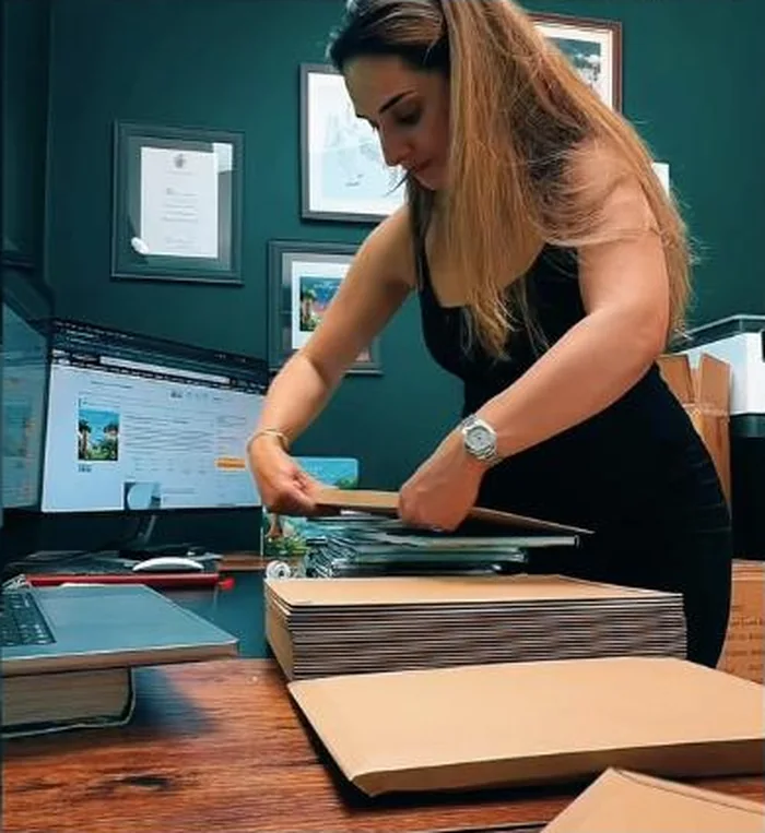 A stack of freshly printed copies being packed into envelopes at a desk